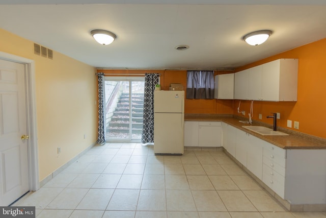 kitchen featuring sink, white fridge, and white cabinets