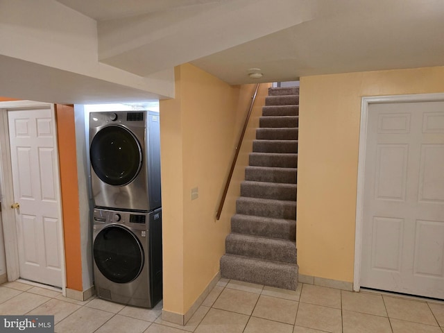 laundry area featuring stacked washer and clothes dryer and light tile patterned floors