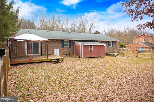 rear view of property with a wooden deck, a gazebo, and a storage unit