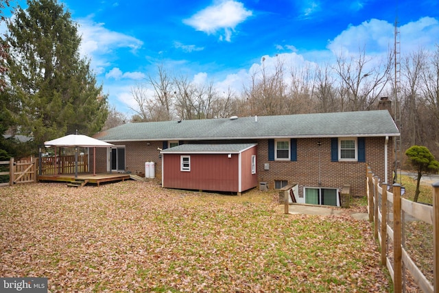 rear view of property featuring a wooden deck, a yard, and a shed