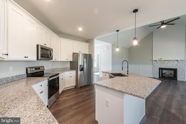 kitchen with appliances with stainless steel finishes, a kitchen island with sink, sink, white cabinets, and lofted ceiling