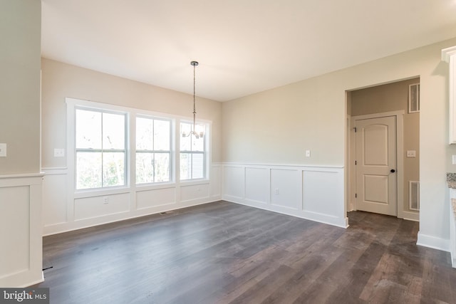 unfurnished dining area with a notable chandelier and dark hardwood / wood-style flooring