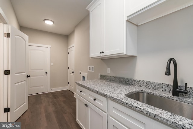 kitchen featuring white cabinets, dark hardwood / wood-style floors, light stone countertops, and sink