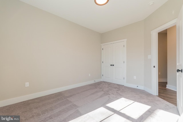 unfurnished bedroom with a closet and light colored carpet