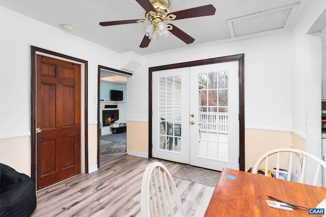 doorway featuring french doors, crown molding, ceiling fan, light wood-type flooring, and a textured ceiling