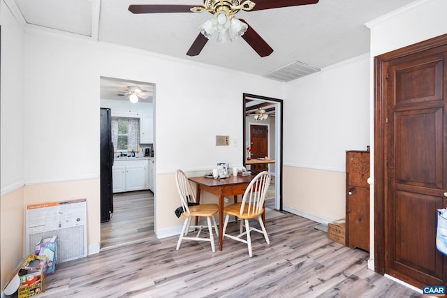 dining room featuring a textured ceiling, light hardwood / wood-style floors, and crown molding