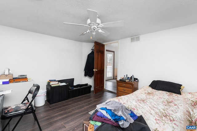 bedroom with a textured ceiling, dark hardwood / wood-style floors, and ceiling fan