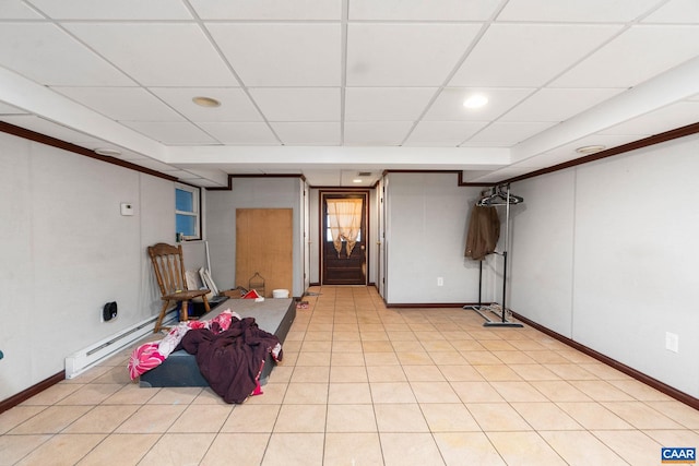 basement featuring a drop ceiling, light tile patterned floors, and a baseboard radiator