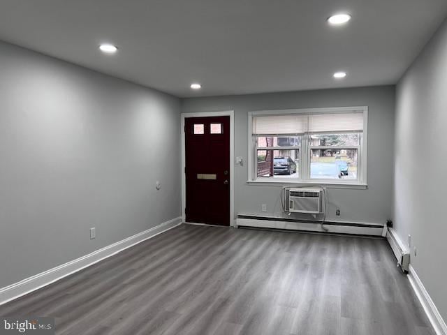 entrance foyer with wood-type flooring, a wall unit AC, and baseboard heating