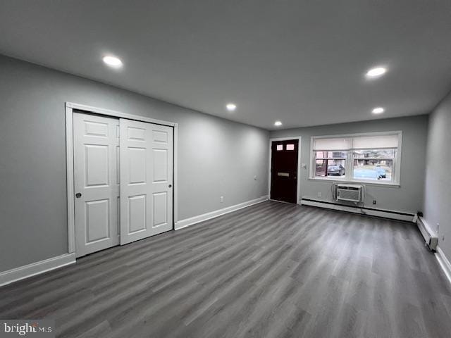 unfurnished living room featuring a wall mounted AC and dark wood-type flooring