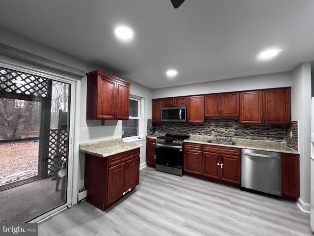 kitchen featuring ceiling fan, sink, decorative backsplash, appliances with stainless steel finishes, and light wood-type flooring