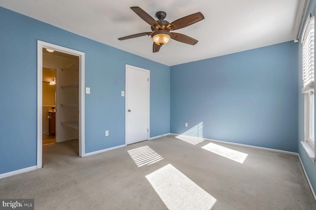 unfurnished bedroom featuring a walk in closet, light carpet, ceiling fan, and a closet