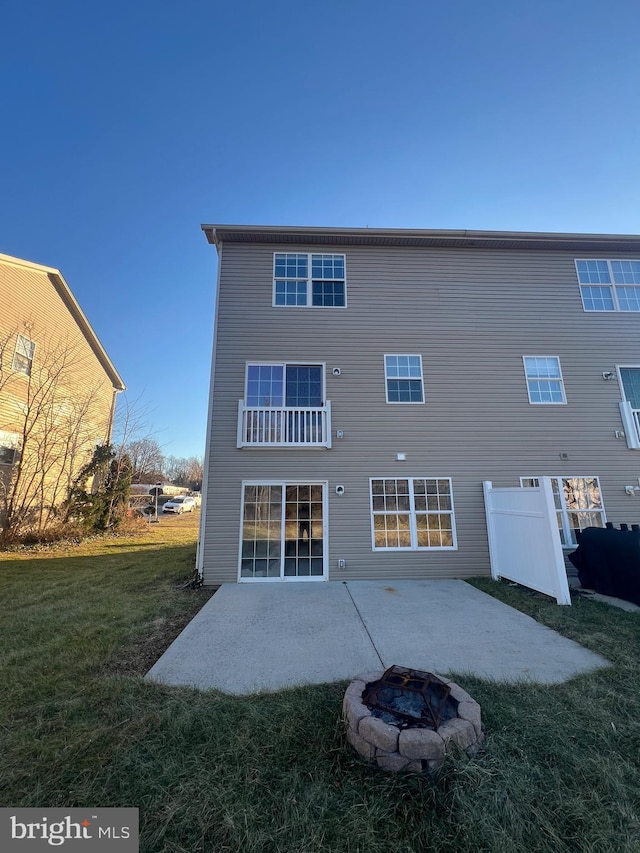 rear view of property featuring a patio area, a yard, and an outdoor fire pit