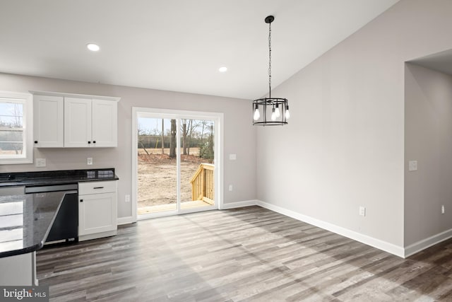 kitchen with white cabinets, vaulted ceiling, dishwasher, hardwood / wood-style floors, and hanging light fixtures