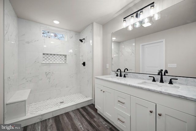 bathroom with a tile shower, vanity, and wood-type flooring