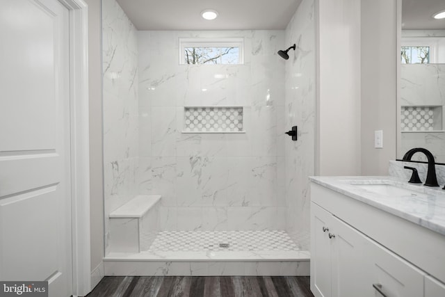 bathroom featuring hardwood / wood-style flooring, vanity, and tiled shower