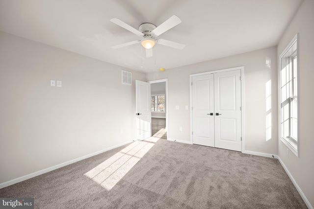 unfurnished bedroom with multiple windows, a closet, ceiling fan, and light colored carpet