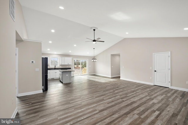 unfurnished living room featuring ceiling fan, hardwood / wood-style floors, vaulted ceiling, and sink