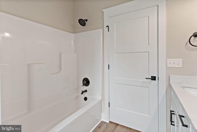 bathroom with hardwood / wood-style flooring, vanity, and shower / bath combination