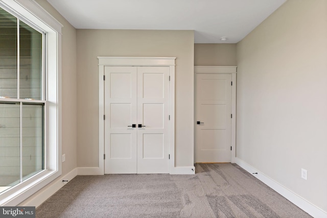 unfurnished bedroom with light carpet and a closet