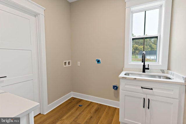 washroom with electric dryer hookup, cabinets, sink, washer hookup, and light wood-type flooring