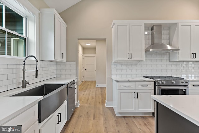 kitchen featuring white cabinets, stainless steel appliances, and wall chimney exhaust hood