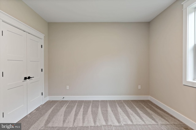 unfurnished bedroom featuring light carpet and a closet