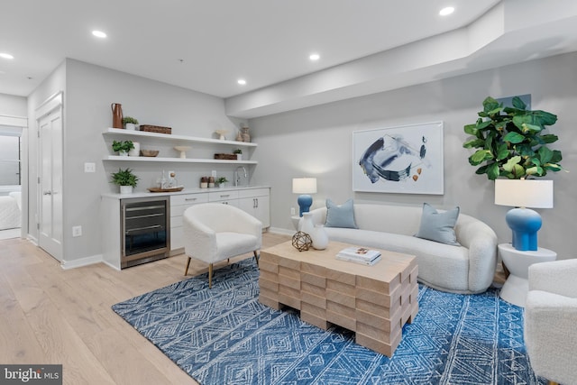 living room with bar, wine cooler, and light wood-type flooring