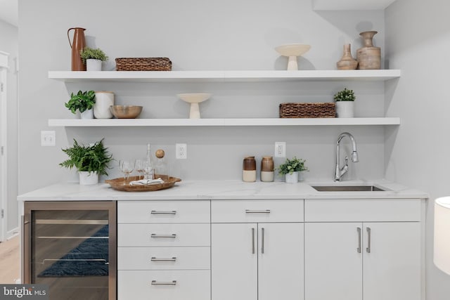 bar with white cabinets, light stone counters, sink, and wine cooler