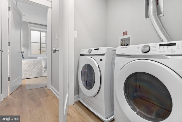 laundry room featuring independent washer and dryer and light hardwood / wood-style floors