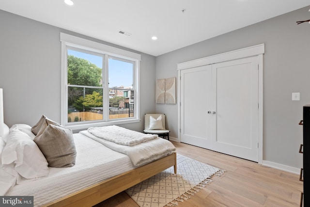 bedroom with light hardwood / wood-style floors and a closet