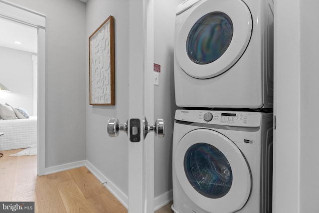 clothes washing area featuring light hardwood / wood-style flooring and stacked washer / drying machine