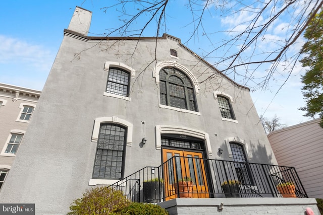 view of front of house with a chimney and stucco siding