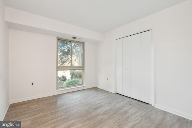 unfurnished bedroom with a closet and light hardwood / wood-style floors