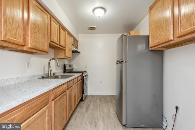 kitchen featuring light stone counters, sink, appliances with stainless steel finishes, and light hardwood / wood-style flooring