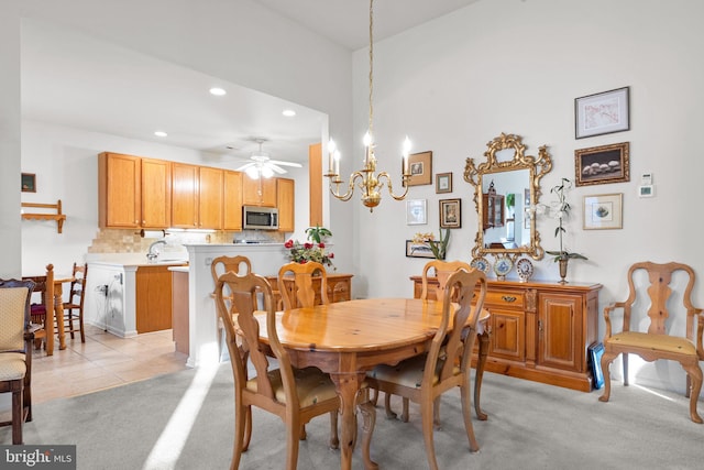 dining space featuring sink, ceiling fan with notable chandelier, and light colored carpet