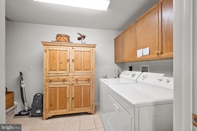 clothes washing area featuring cabinets, washing machine and dryer, light tile patterned floors, and a skylight