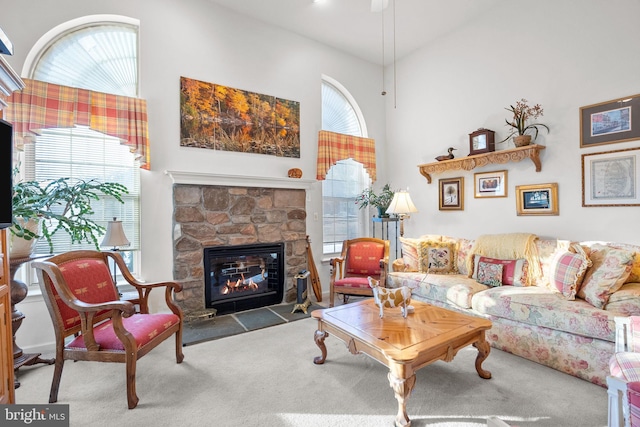 carpeted living room featuring a fireplace and a high ceiling