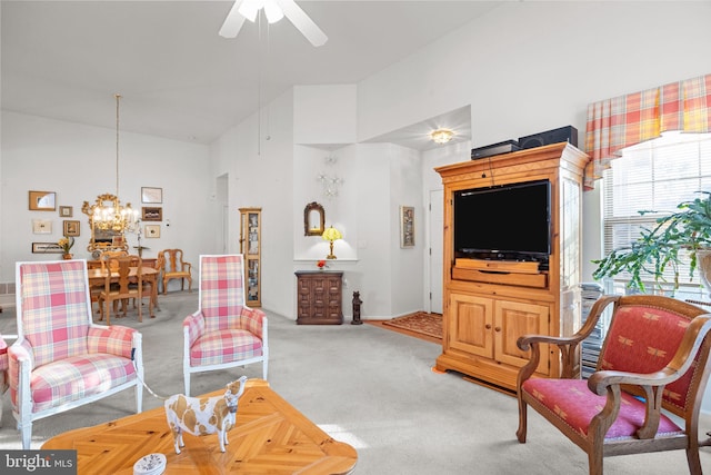 carpeted living room with ceiling fan with notable chandelier and high vaulted ceiling