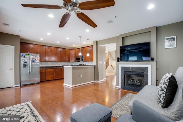 kitchen featuring decorative backsplash, appliances with stainless steel finishes, ceiling fan, light hardwood / wood-style flooring, and hanging light fixtures