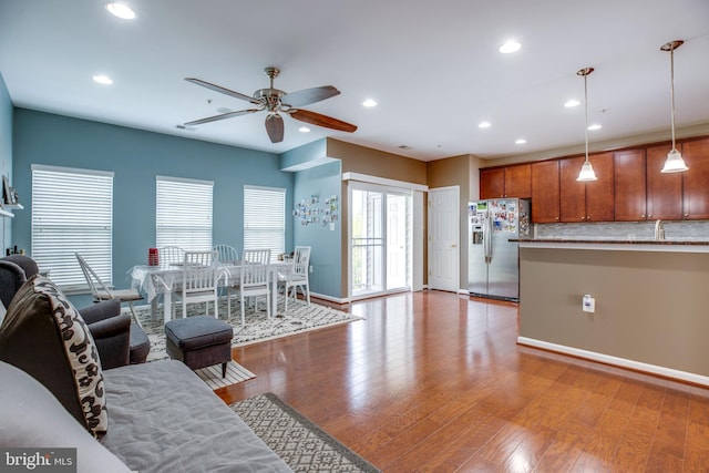 living room featuring ceiling fan, sink, and light wood-type flooring