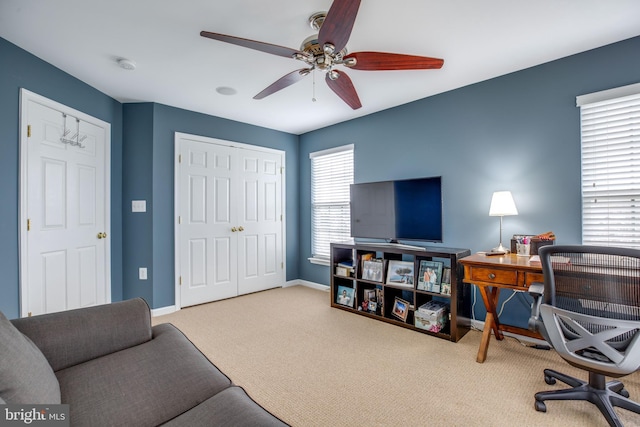 carpeted office space with plenty of natural light and ceiling fan