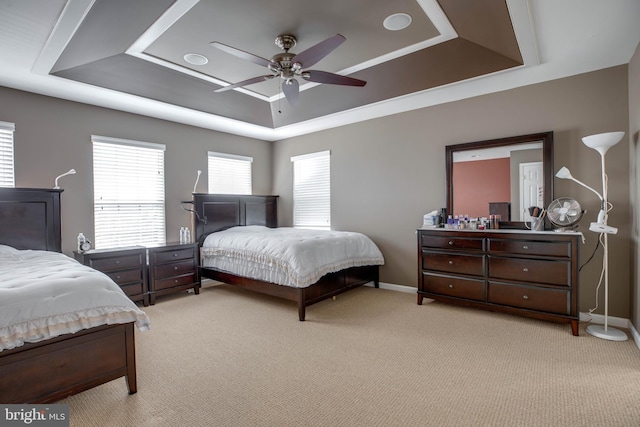 carpeted bedroom with ceiling fan and a tray ceiling