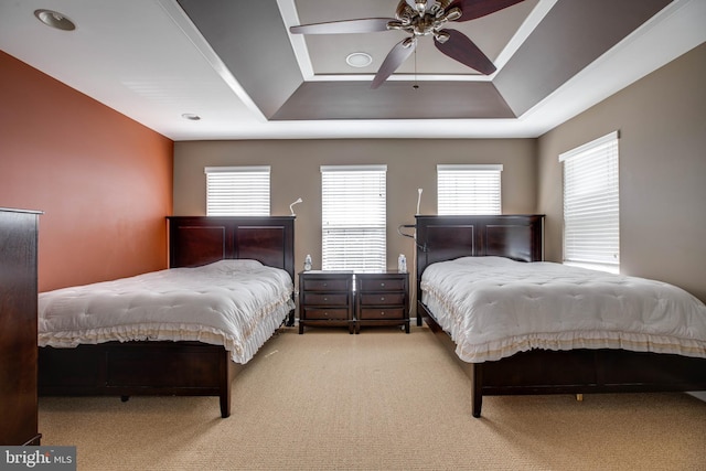 carpeted bedroom featuring a raised ceiling and ceiling fan