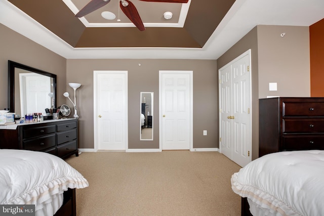 carpeted bedroom featuring a tray ceiling and ceiling fan