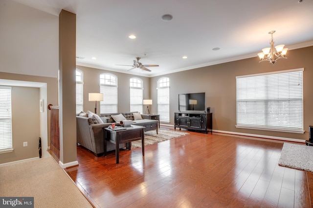 living room featuring ceiling fan with notable chandelier, wood-type flooring, and ornamental molding