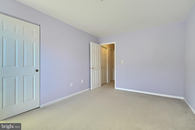 unfurnished bedroom with light colored carpet and a closet