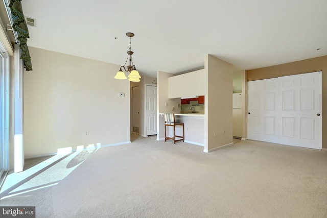 unfurnished living room featuring light colored carpet and a notable chandelier