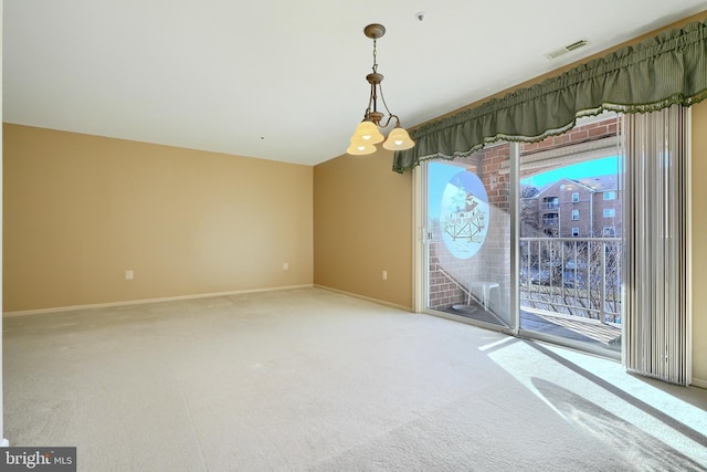 carpeted empty room featuring a chandelier