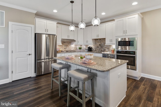 kitchen featuring a center island, pendant lighting, white cabinets, and stainless steel appliances